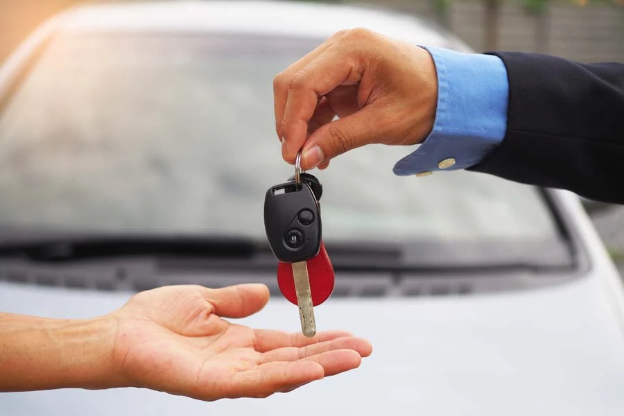 Remise de cl&eacute;s de v&eacute;hicule entre deux personnes dans un environnement automobile professionnel