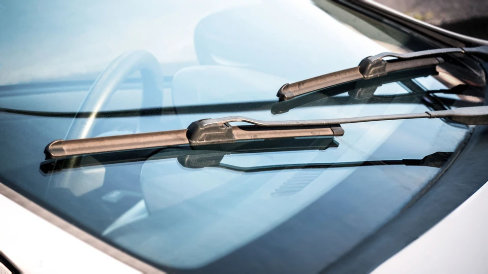 Main sur vitre de véhicule pointant vers impact d'éclat sur pare-brise automobile