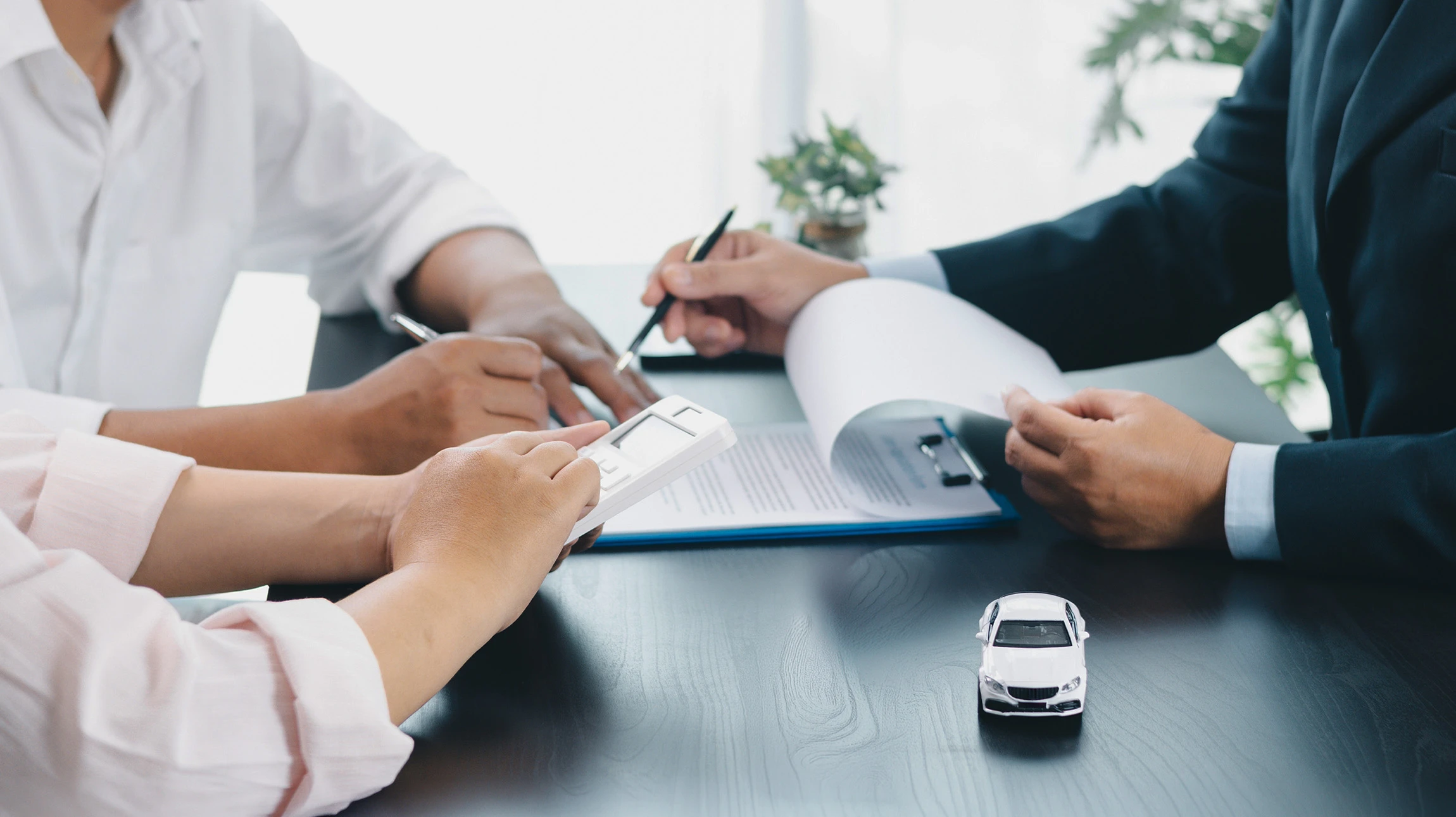 Deux techniciens en combinaison bleue remplacent un pare-brise automobile dans un atelier vitré