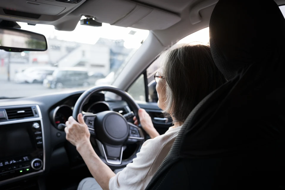 Femme souriante dans voiture rouge tenant clés de véhicule par la fenêtre ouverte, faisant signe de pouce levé