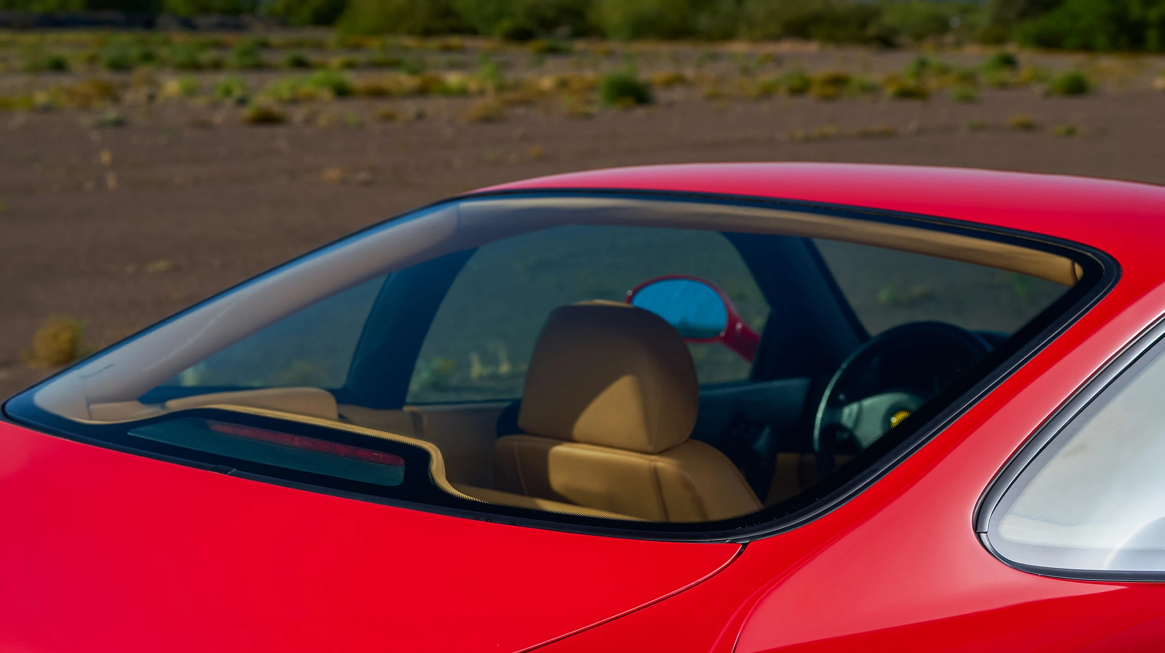 Conducteur au volant d'un véhicule circulant sur route forestière, rétroviseur latéral reflétant une autoroute ensoleillée avec autre véhicule