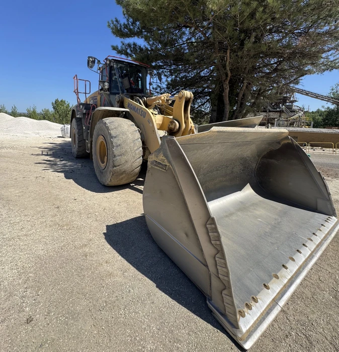 Deux techniciens en combinaison bleue remplacent un pare-brise automobile dans un atelier vitré
