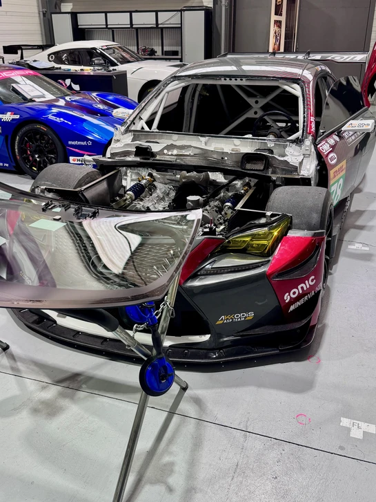 Technicien automobile en combinaison de travail et casquette effectuant un diagnostic sur v&eacute;hicule blanc dans un garage moderne
